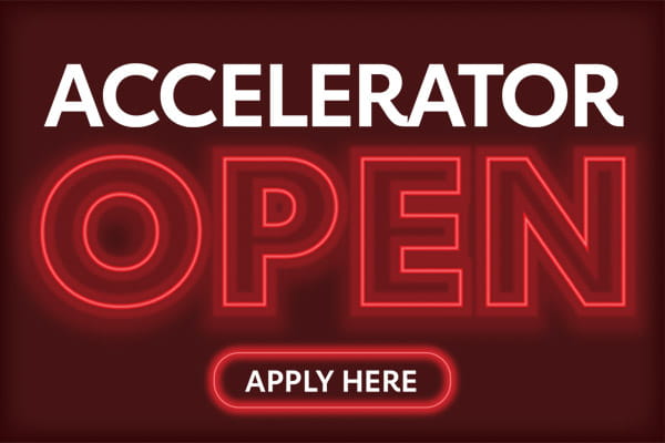 A digital graphic shows "accelerator" in bold white letters on top of "open" in the style of a red neon sign. The words "apply here" appear along the bottom.
