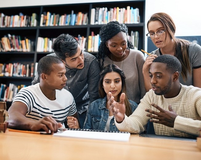 A group of diverse college students meeting in a library.