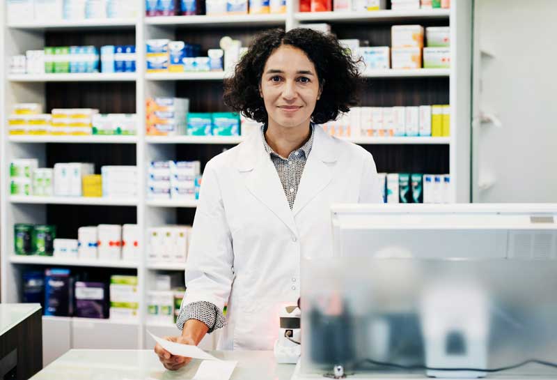 pharmacist holding prescription behind the counter