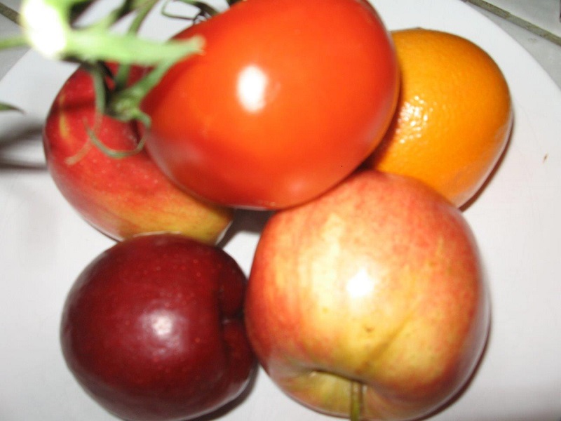 A bowl with apples, an orange and tomato
