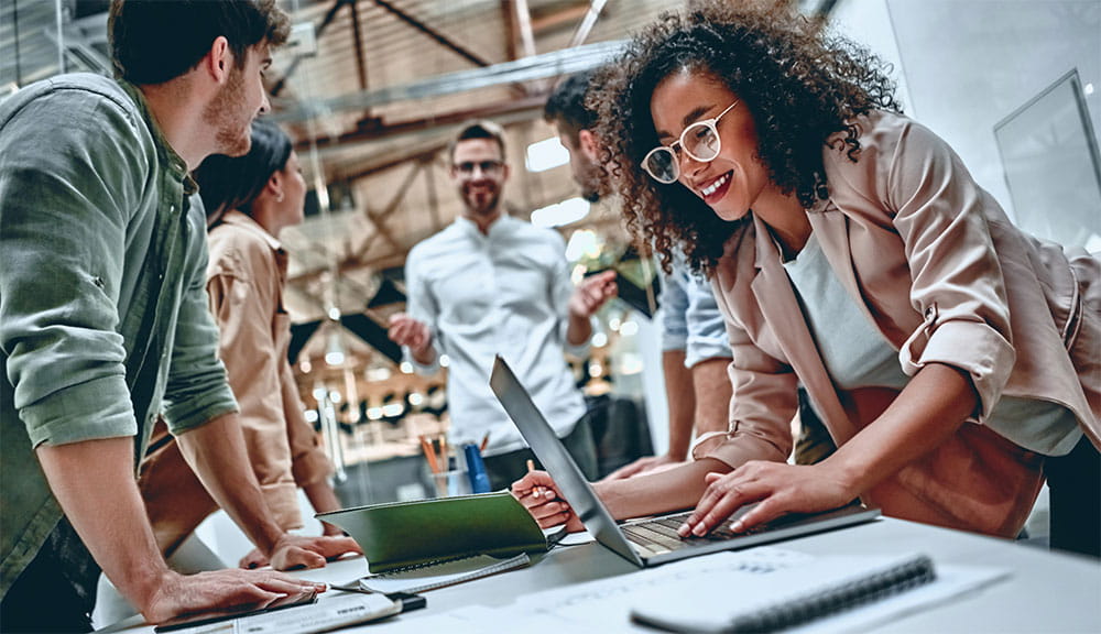 a diverse group of coworkers meeting in an office around a table of digital devices a diverse group of coworkers meeting in an office around a table of digital devices