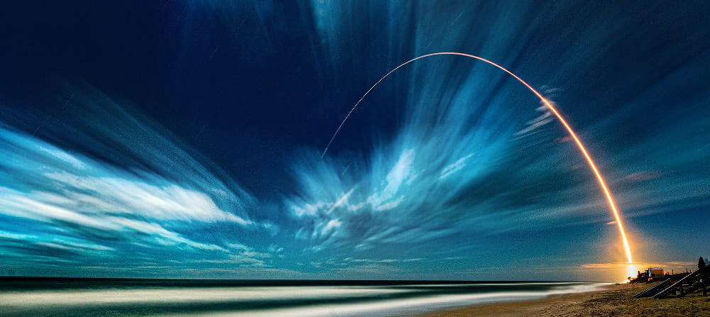 conceptual landscape of a beach and night sky with a gold streak arching over the ocean conceptual landscape of a beach and night sky with a gold streak arching over the ocean
